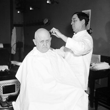 an almost bald man receiving a hair cut in a barber shop ca december 1935