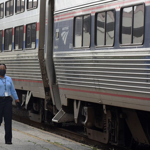 amtrak employee with face mask next to train
