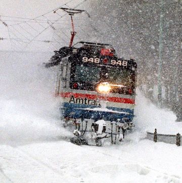 An Amtrak train blasts through a snow drift, as it runs thro
