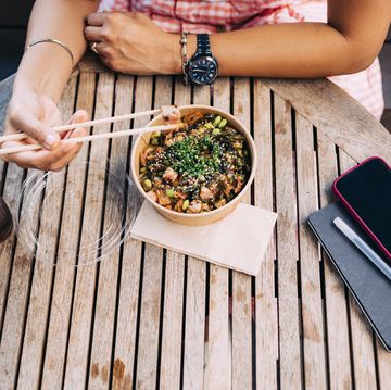 an anonymous businesswoman having outdoor lunch using chopsticks