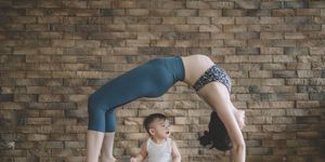 an asian chinese female yoga instructor with bridge pose while her son looking at her