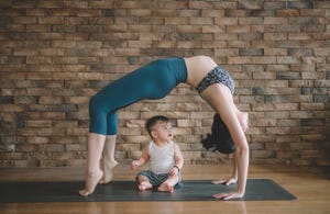 an asian chinese female yoga instructor with bridge pose while her son looking at her