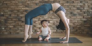 an asian chinese female yoga instructor with bridge pose while her son looking at her