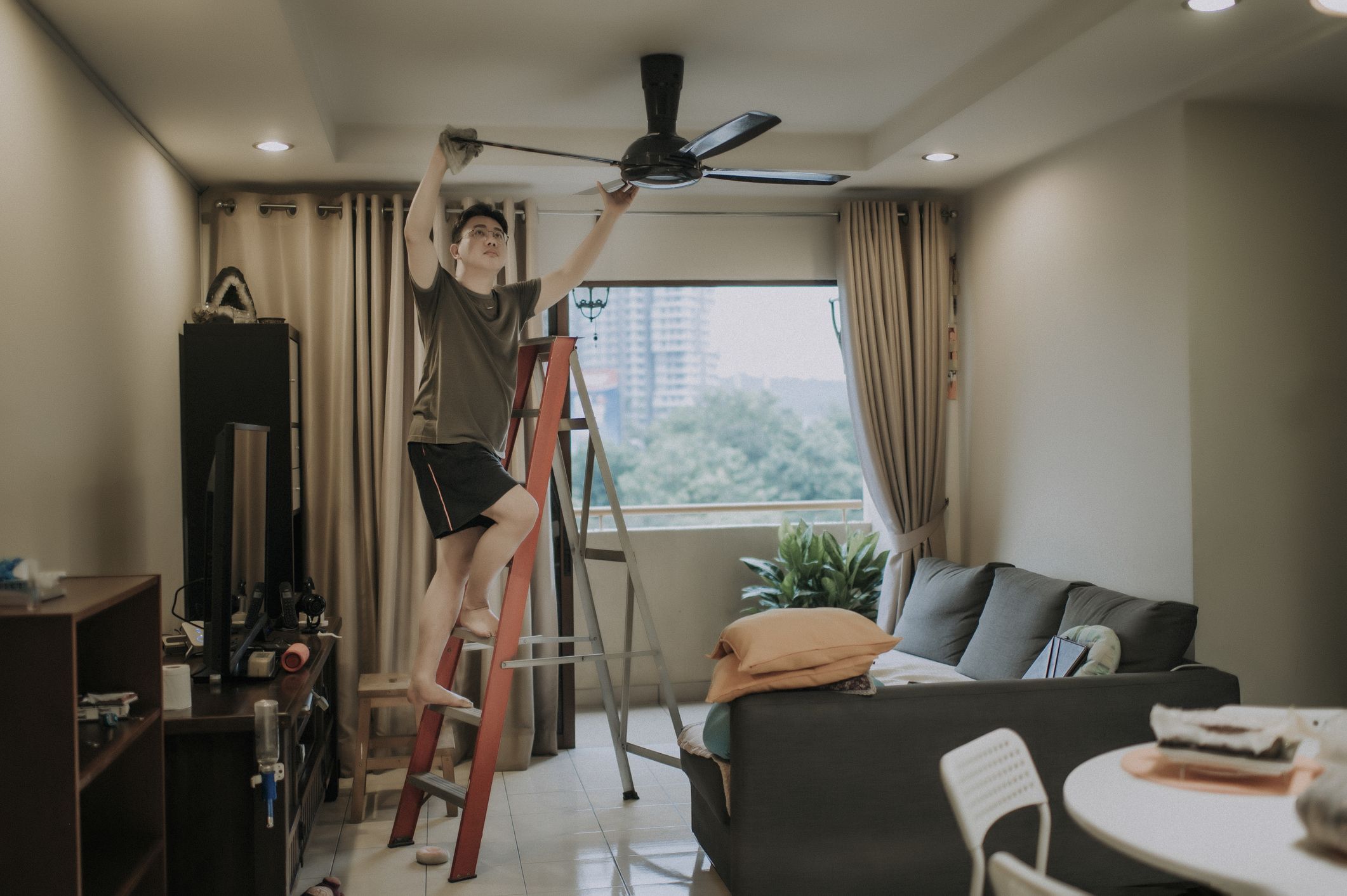 https://hips.hearstapps.com/hmg-prod/images/an-asian-chinese-male-cleaning-ceiling-fan-at-home-royalty-free-image-1619537903.