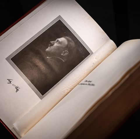 a book seen from overhead is open to a page with a portrait of a man looking left, an autograph signature is written below the picture