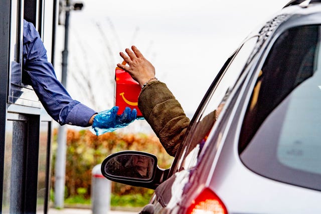 an employee wearing gloves as a protection seen giving food