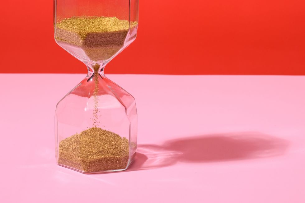 an hourglass on red and pink background