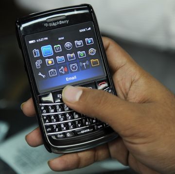 a closeup of a hand holding a blackberry smartphone, with several icons visible on the screen