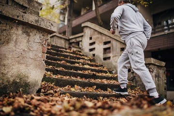 an older man exercises on the steps with autumn leaves