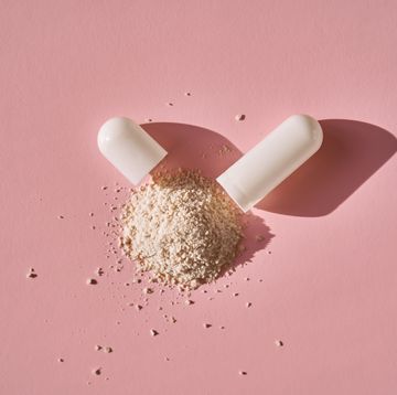 an open capsule with its contents on a pink background