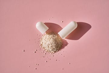 an open capsule with its contents on a pink background