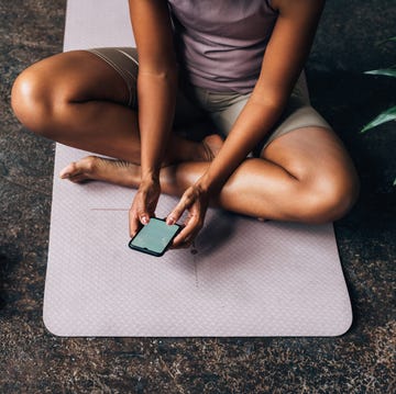 an unrecognizable beautiful woman using her mobile phone after doing her workout