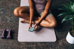 an unrecognizable beautiful woman using her mobile phone after doing her workout