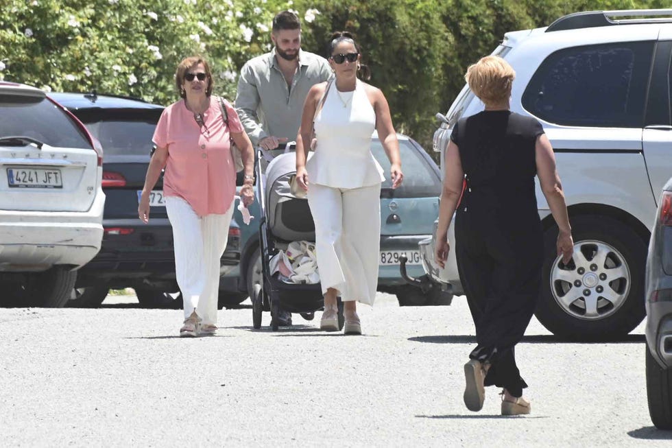 group of people walking in a parking area with a stroller and cars