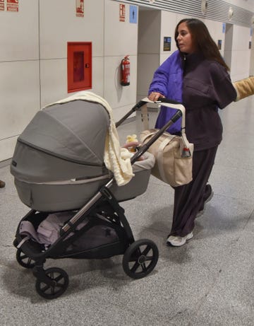 la influencer, con un chandal gris y abrigo azul, con el carrito de su hija alma