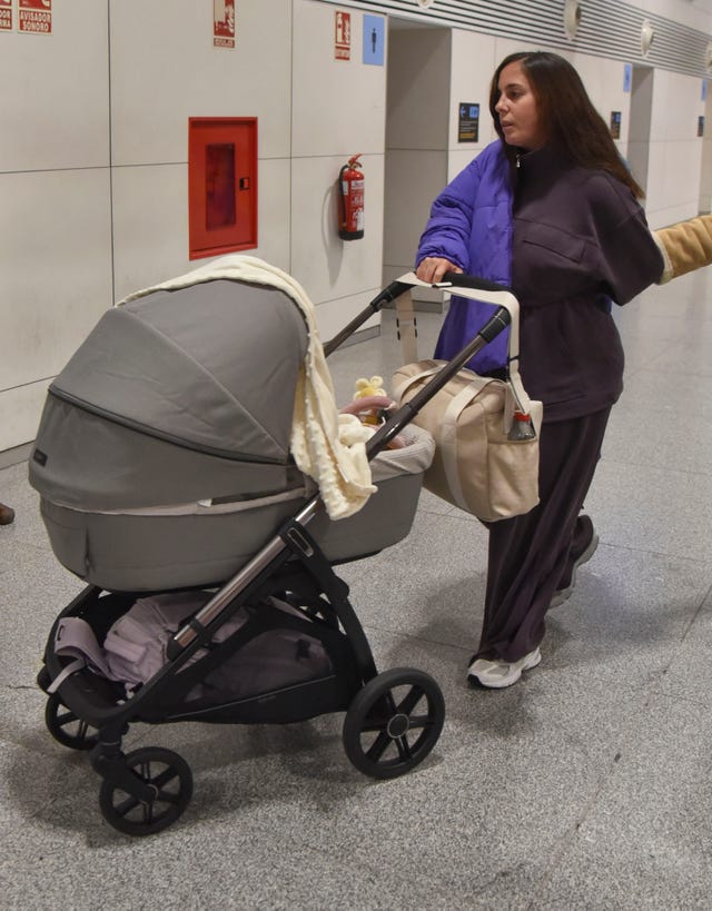 la influencer, con un chandal gris y abrigo azul, con el carrito de su hija alma