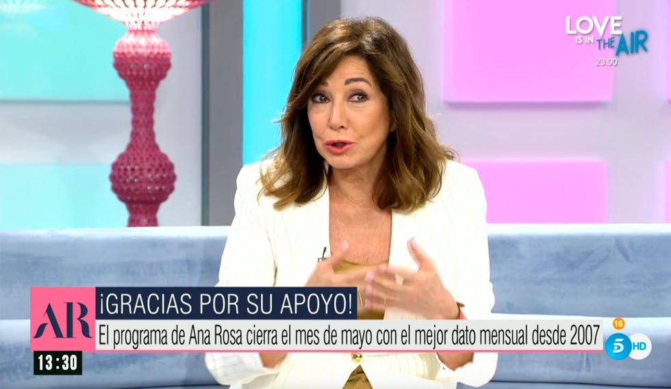 la presentadora, con un traje blanco, da las gracias por sus buenos datos de audiencia