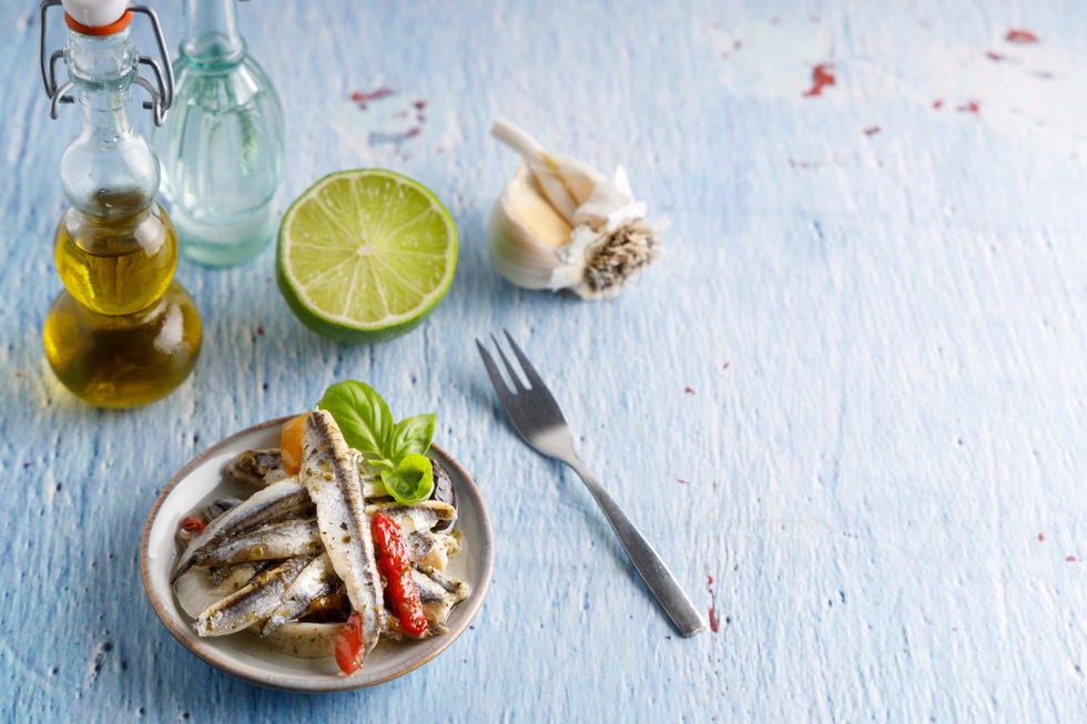 mediterranean appetizer, anchovy fish in olive oil and herbs in a small bowl.