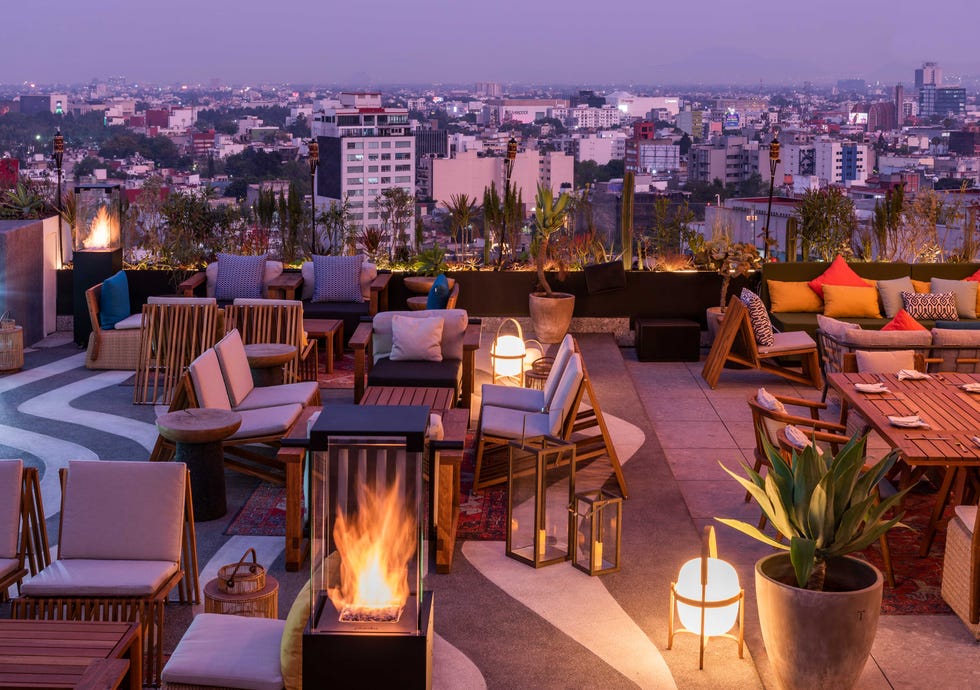 a patio with chairs and tables with a fire in the middle