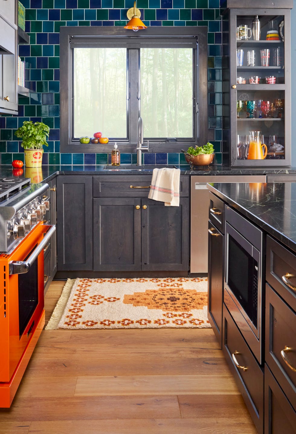 modern kitchen with black stained cabinetry, blue tile, and orange range