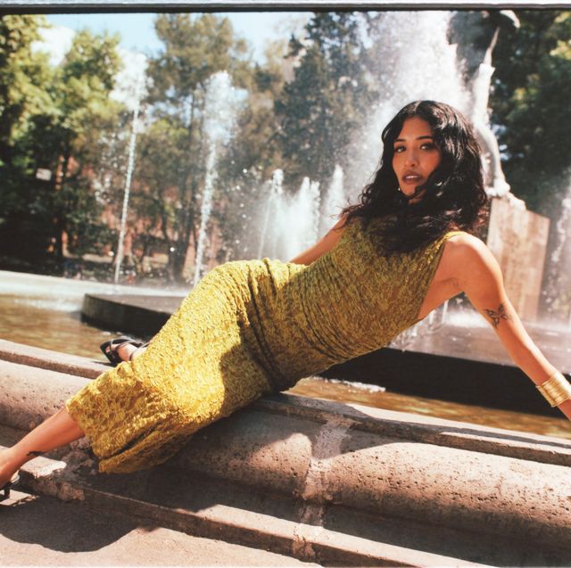 a person in a dress sitting on a fountain