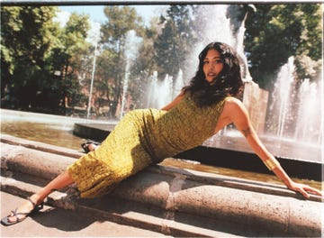 a person in a dress sitting on a fountain