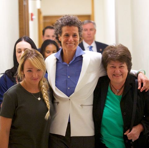 andrea constand with her lawyers wearing a white blazer and blue top walking through court
