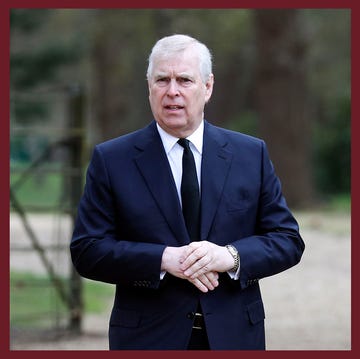 a man in a suit standing in front of a brick building