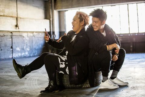 androgynous asian man and woman posing for cell phone selfie