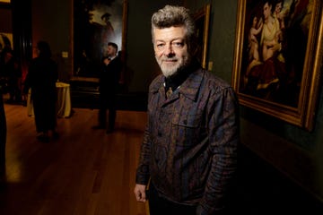 andy serkis stands in a room full of paintings