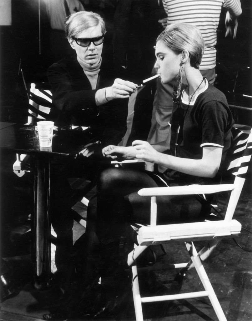 circa 1965 american pop artist andy warhol 1928 1987 sits next to actor edie sedgwick 1943 1971 and lights her cigarette, on the set of one of his films photo by walter daranhulton archivegetty images