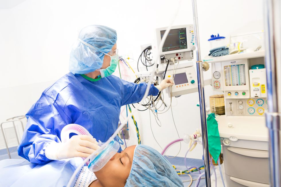 Anesthesiologist checking monitors while sedating patient for surgery in hospital