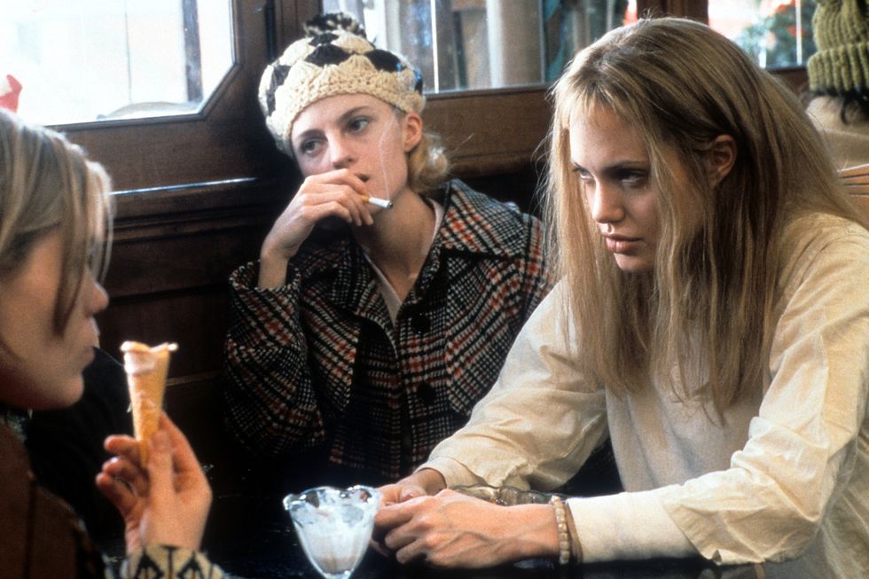 clea duvall and angelina jolie in a scene from 'girl, interrupted' they sit at a table as a woman sits across from them