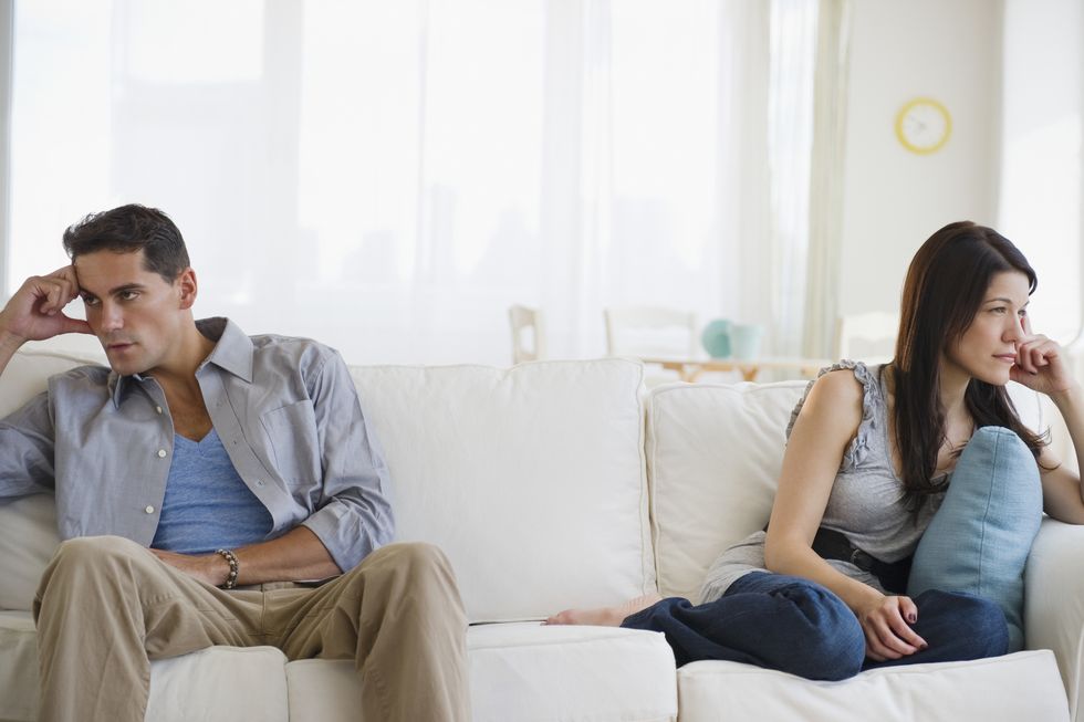 angry mixed race couple having argument on sofa