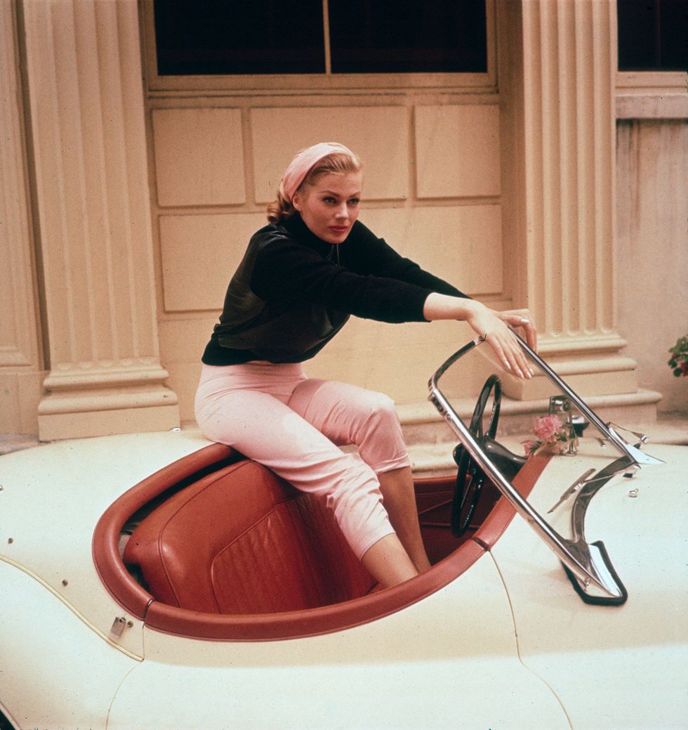 circa 1955  exclusive a portrait of swedish actor anita ekberg sitting on the trunk of a cream convertible with her feet in its red leather interior, hollywood, california ekberg wears cream colored capri pants, a black top and a scarf in her hair  photo by gene lestergetty images