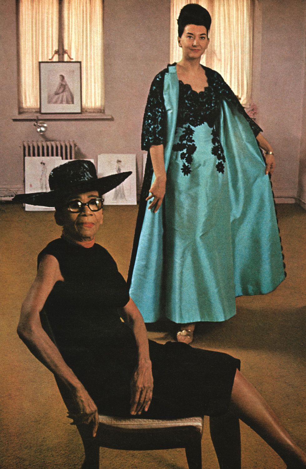 dean of fashion designers, ann lowe of new york city, who has been creating beautiful dresses and hand made flowers since when was a child of six she is pictured with london model judith palmer, wearing lowe theater gown and coat of italian mecado silk, with black lace reembroidered in black soutache moneta sleet, jrljohnson publishing archive