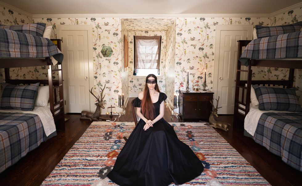 a blindfolded woman in a dress posing for a picture in a bedroom
