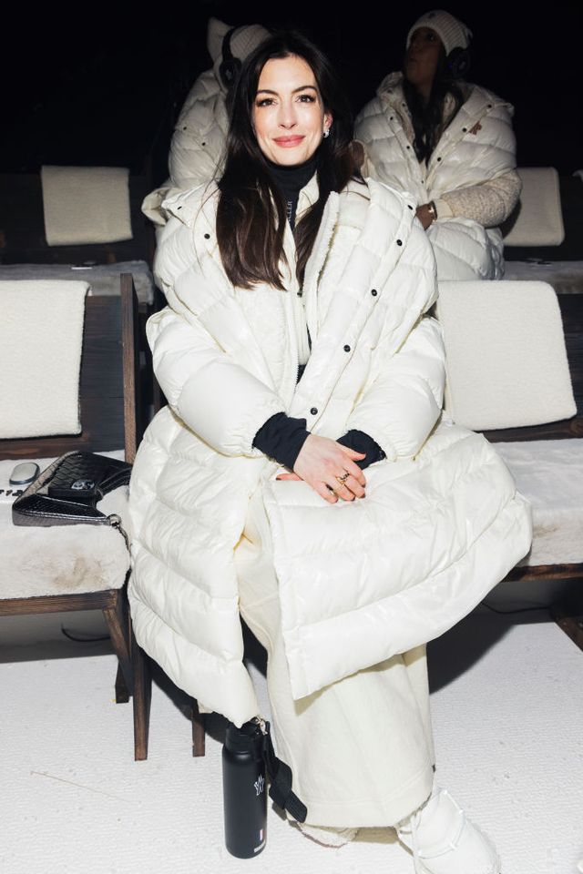 anne hathaway in a white puffer coat at the moncler grenoble rtw fall 2024 front row
