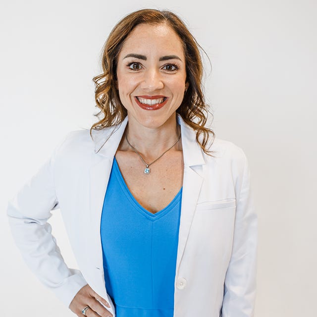 medical professional in a white coat over a blue dress posed with one hand on her hip medical professional in a white coat over a blue dress posed with one hand on her hip