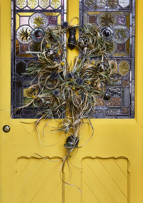 a bright yellow door with a wreath and stained glass