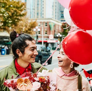 couple on city street holding bouquet and red and pink balloons