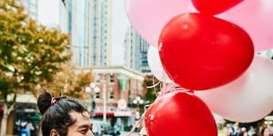 couple on city street holding bouquet and red and pink balloons