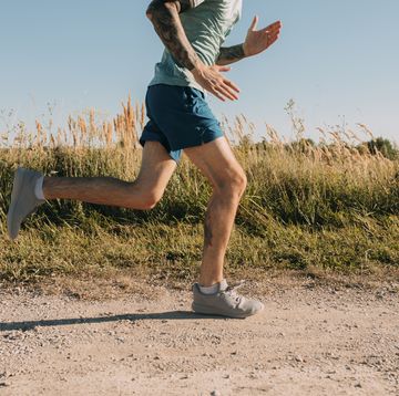 anonymous fit man running in the countryside, cardio workouts concept