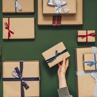 anonymous person holding one of many gift boxes on a green background