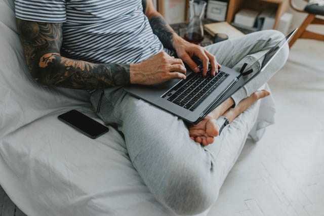 negatieve gevolgen van zitten, man works from home sitting on couch