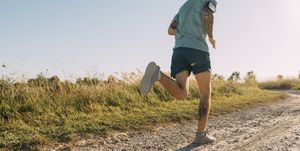 anonymous white sportsman running on a dirt road on a sunny day