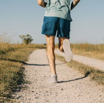 anonymous white sportsman running on a dirt road on a sunny day