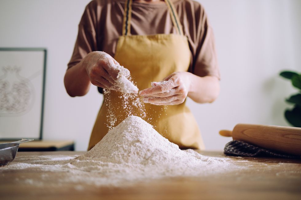 anonymous woman adding and preparing flour for kneading