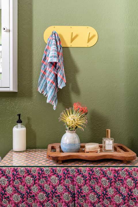 bathroom with green wall and yellow hooks for towels