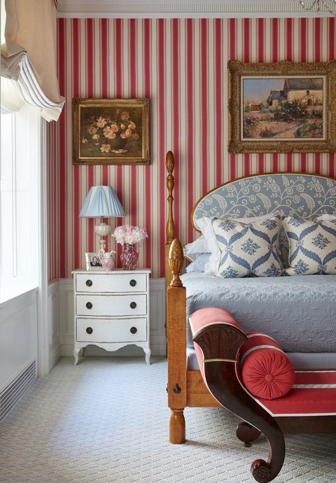 a luxe bedroom with red and white striped walls and blue and white bedding